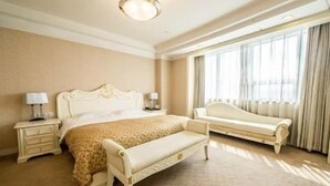 A spacious bedroom with a large bed, a bedside table, a bench, and a window with curtains. - Hongyi Hotel Wuhan University (Wuhan)
