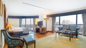 Une chambre d’hôtel équipée d’un lit, d’un bureau, d’une télévision, d’un canapé et offrant une vue sur le panorama urbain.