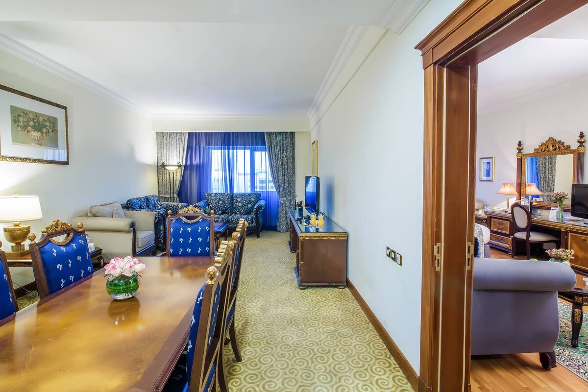 A well-furnished living room with a dining table, chairs, sofas, and a large mirror.