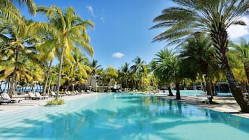 Una piscina al aire libre, sombrillas, sillones reclinables de piscina