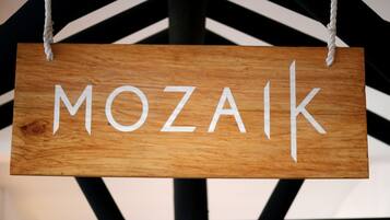 A wooden sign with the word "MOZAIK" hanging from a rope.