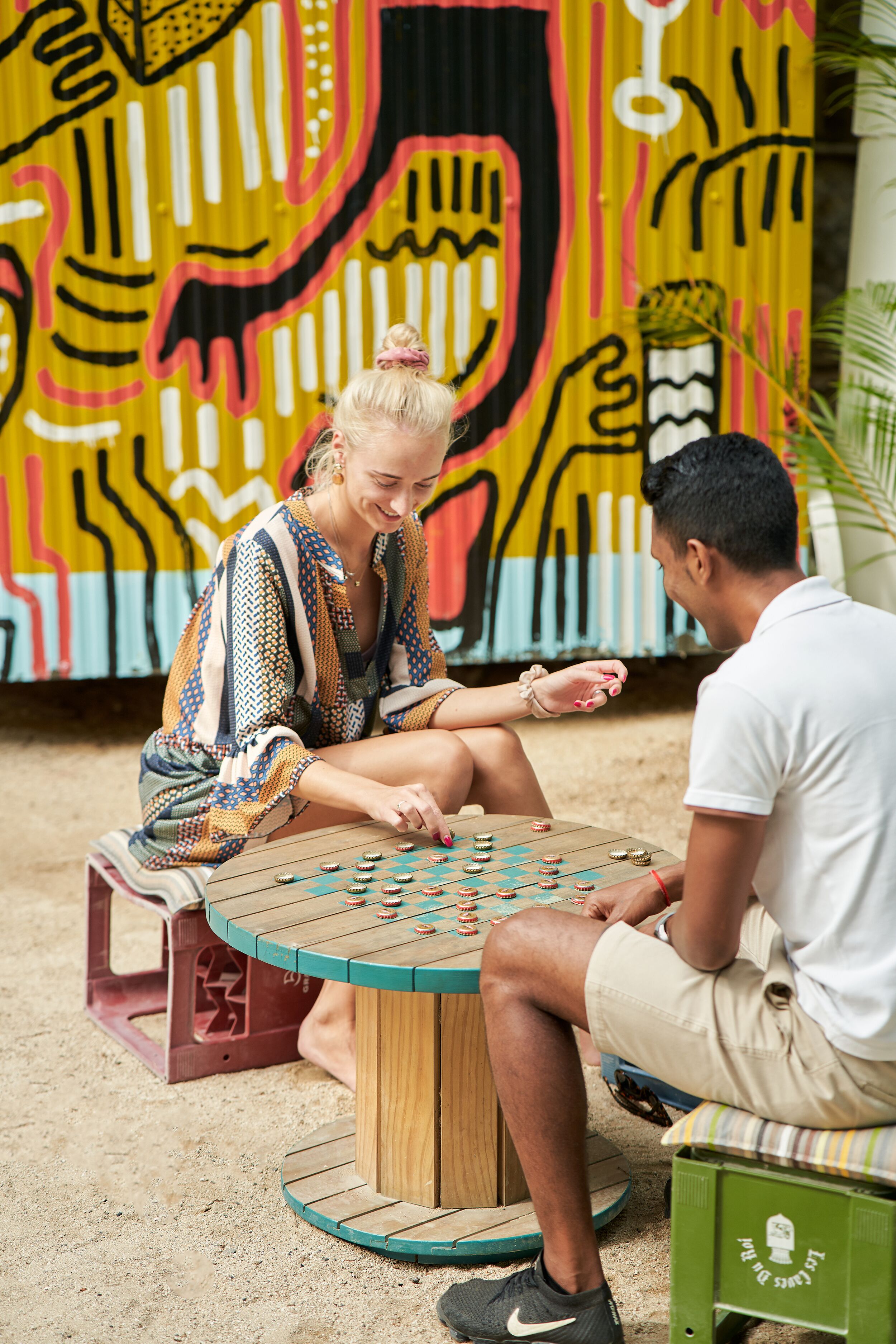 Two people playing a board game on a wooden table outdoors.