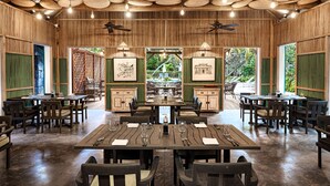 Un restaurante con paredes y techo de madera, varias mesas con sillas, y lámparas colgantes.