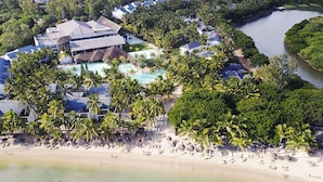 Vista aérea de un resort con piscina, playa y palmeras.