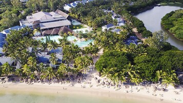 Vista aérea de un resort con piscina, playa y palmeras.