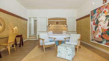 Une chambre spacieuse avec un grand lit, deux tables de chevet, une chaise et une petite table.