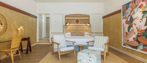 Ruime slaapkamer met een groot bed, twee nachtkastjes, een stoel en een klein tafeltje.
