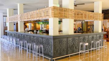 A bar area with a wooden slatted roof, clear plastic stools, and a 'No Smoking' sign.