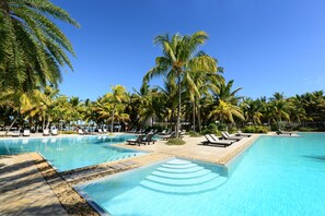 A swimming pool with lounge chairs and palm trees. - The Ravenala Attitude (Balaclava)