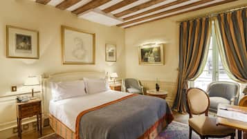A hotel room with a large bed, a desk, a chair, and a window with curtains.