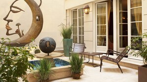 A courtyard with a pool, seating area, and a large moon sculpture.