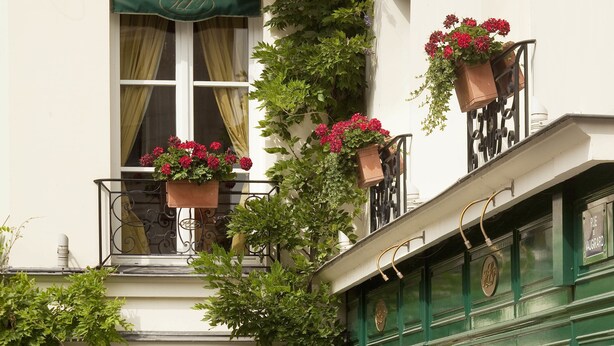 A building with a balcony adorned with hanging flower baskets and a green awning.