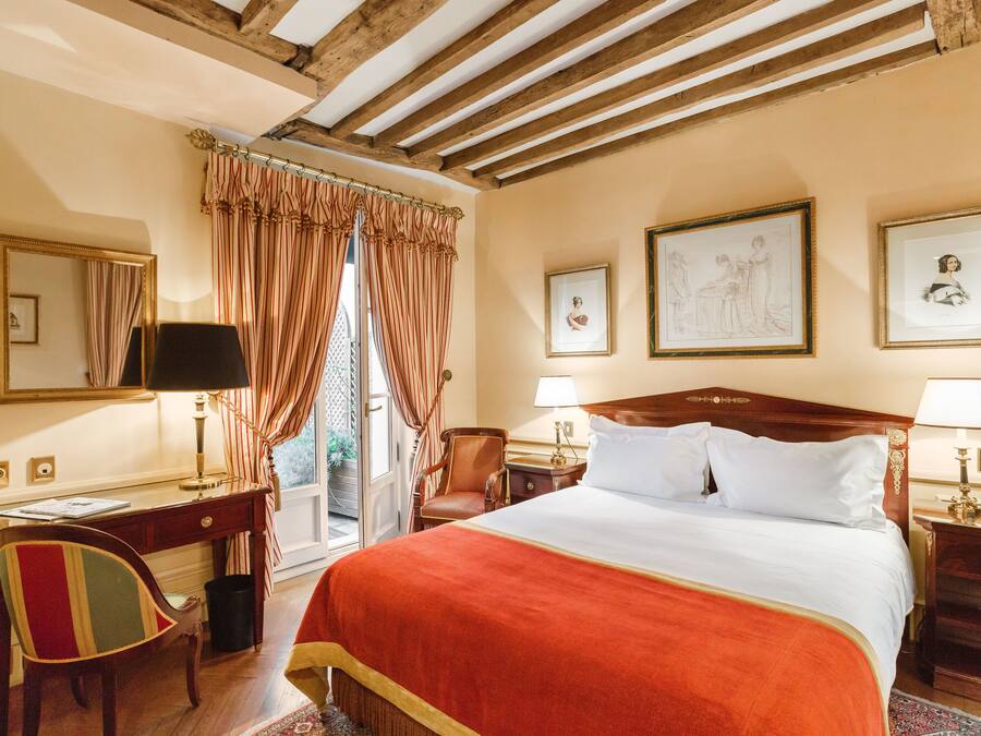 A hotel room with a large bed, a desk, a chair, and a window with curtains.