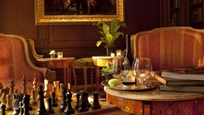 A chessboard, a table with a candle, a vase with a plant, and a painting on the wall.