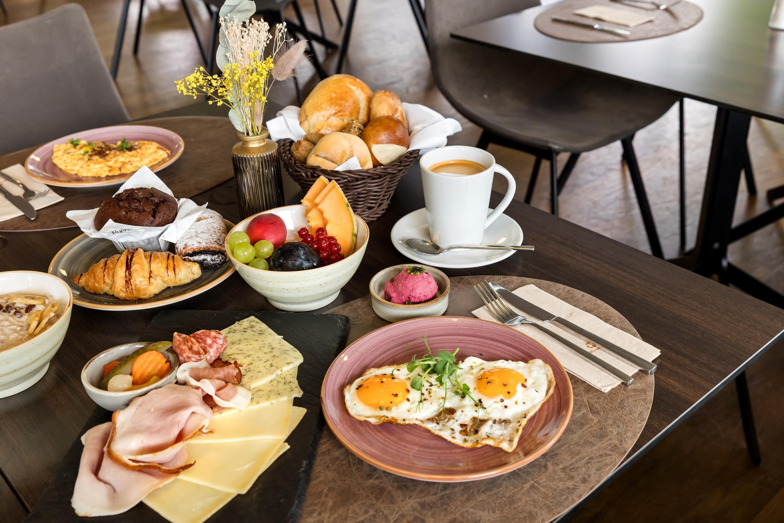 Ett frukostbord med olika sorters mat, inklusive ägg, bakverk och en kaffekopp.