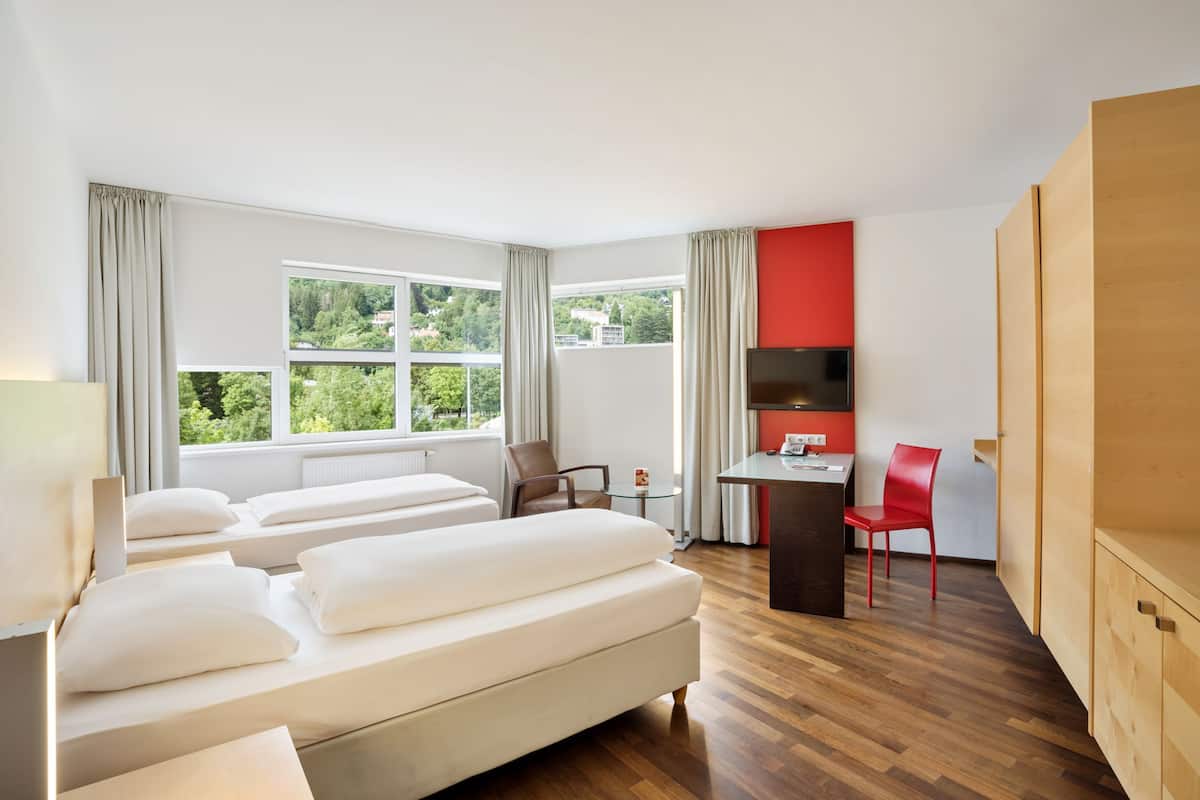 Camera d'albergo con due letti, una scrivania, una sedia e una televisione.