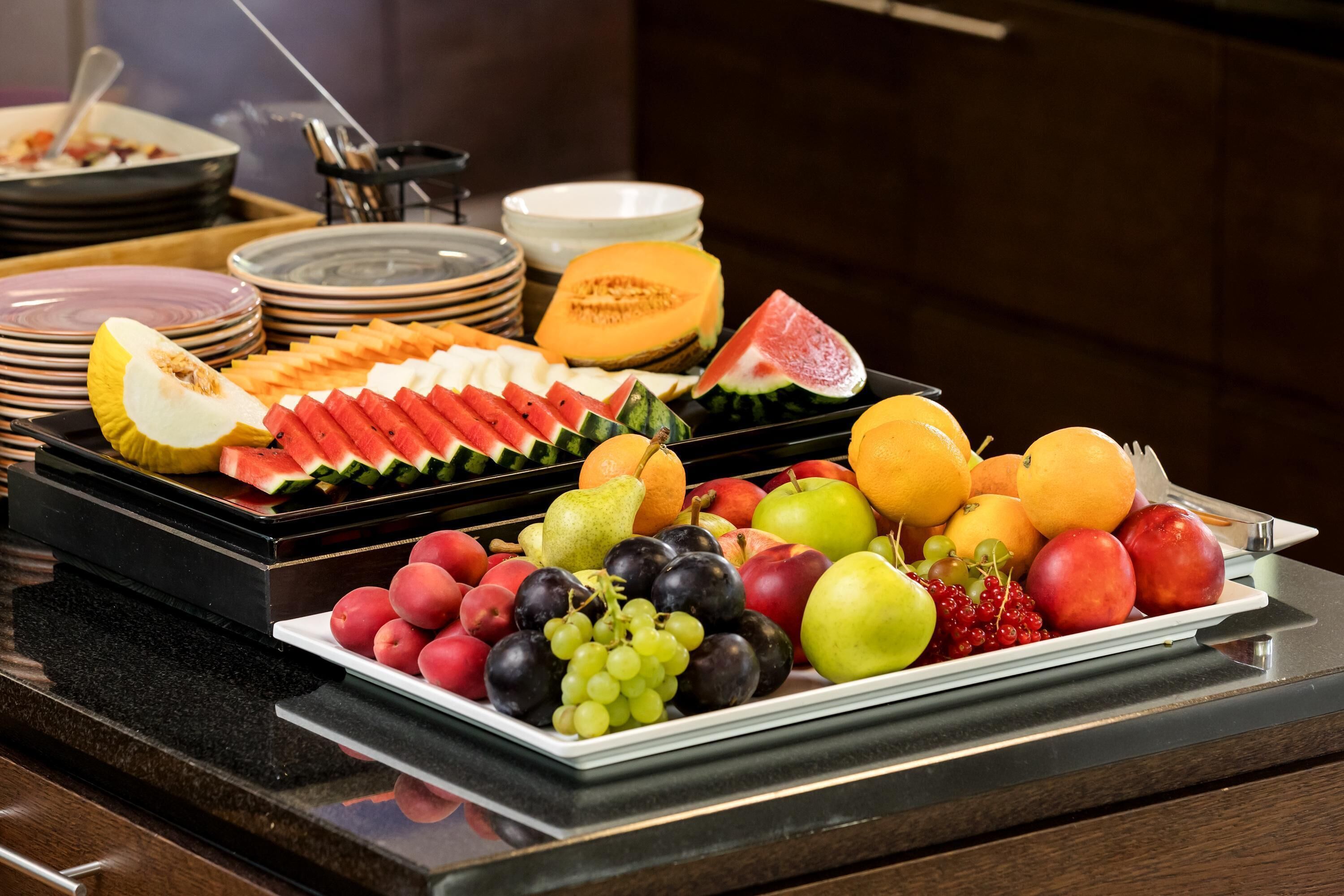 A buffet table with various fruits and dishes.
