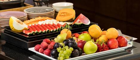A buffet table with various fruits and dishes.