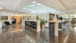 Una hall d'albergo moderna con reception, angolo salotto e bar.