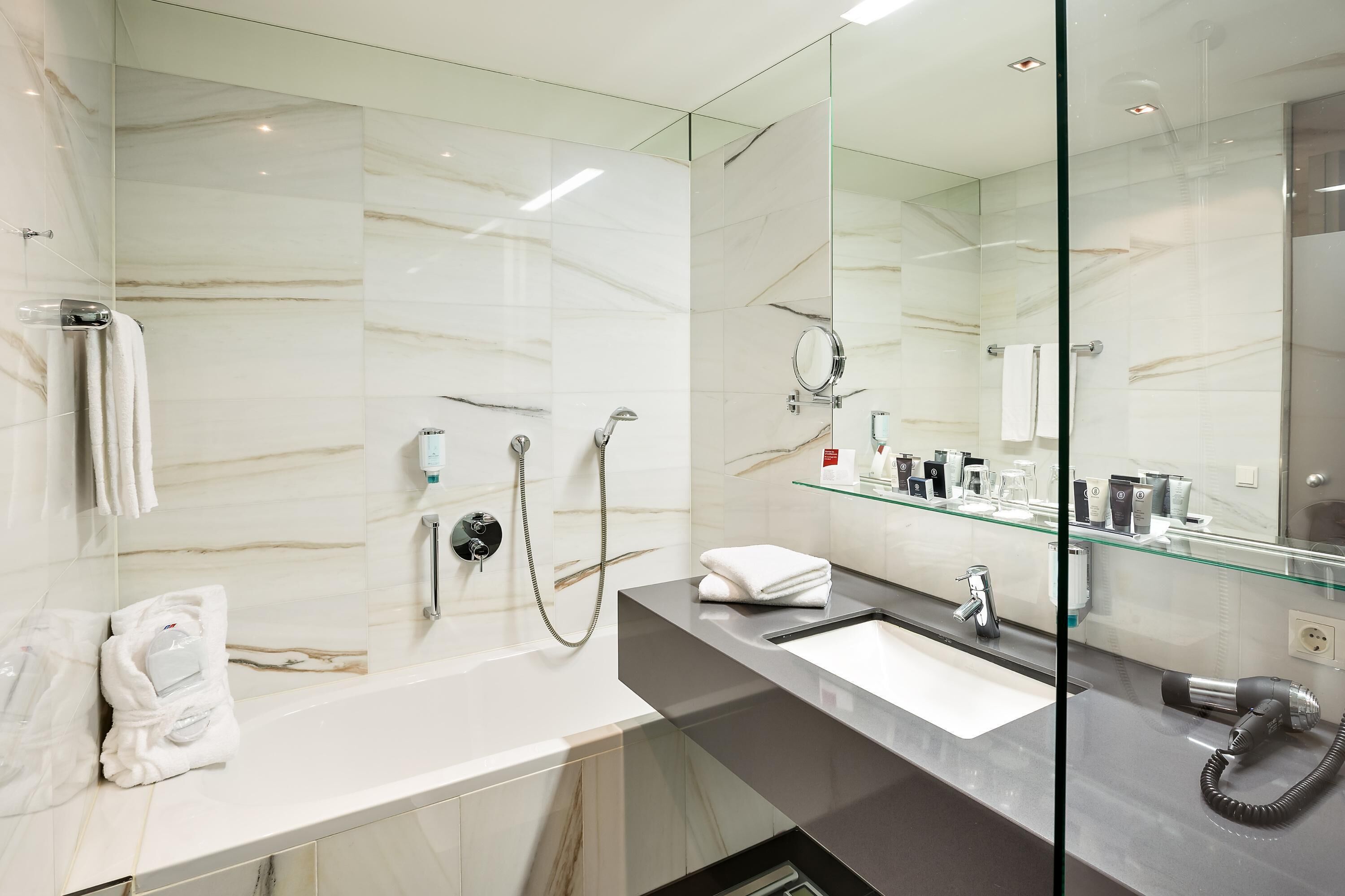 A modern bathroom with a glass shower enclosure, a large mirror, and a vanity with a sink and towel rack.