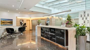 Una moderna area reception con soffitto in vetro, una scrivania reception e un'area relax con poltrone.
