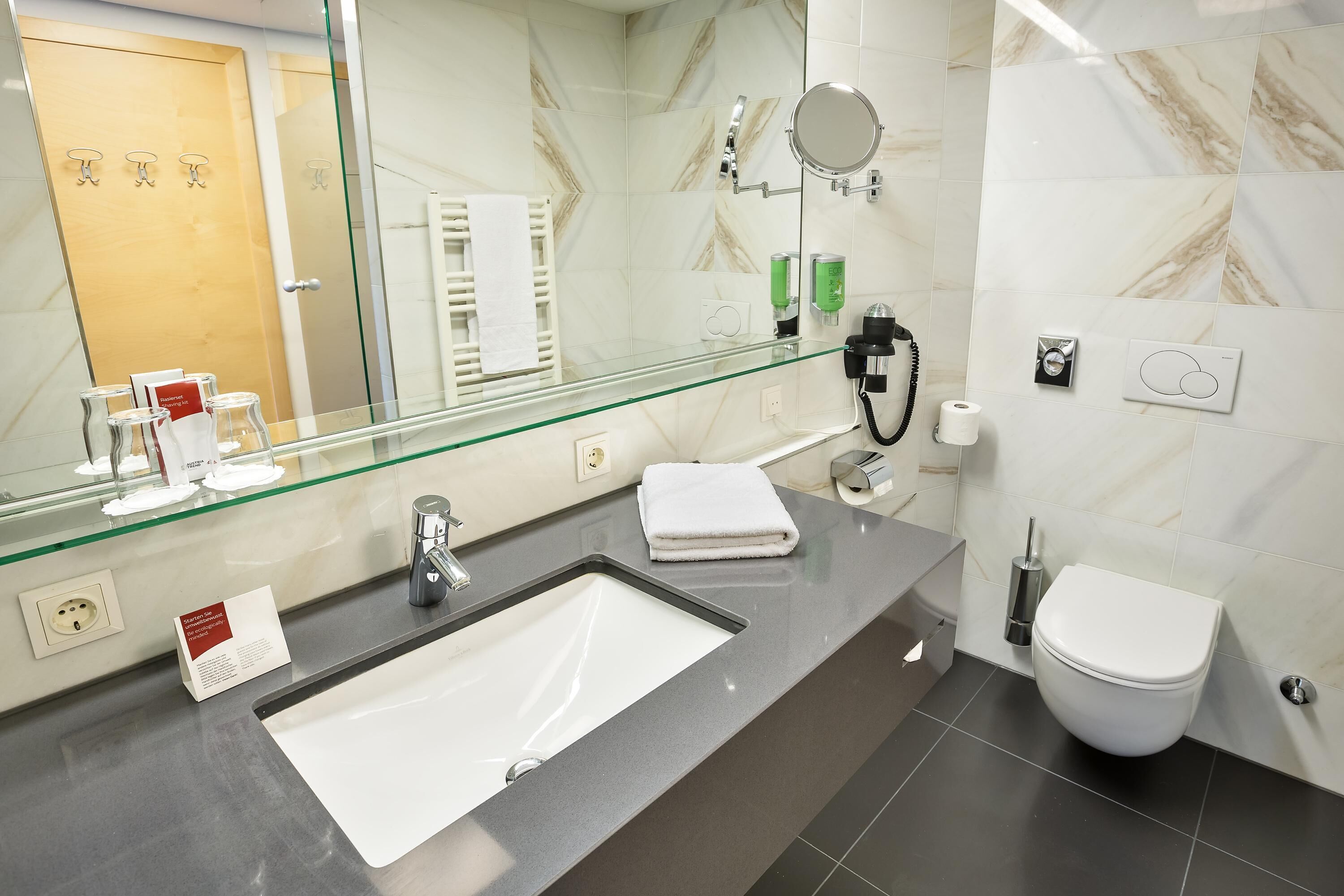 A modern bathroom with a glass shower enclosure, a white sink, and a toilet.