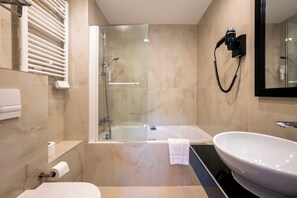 Une salle de bain moderne dotée d’une douche à parois de verre, d’une baignoire sur pied et d’un lavabo indépendant.