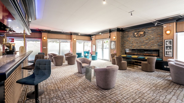 A modern lounge area with a fireplace, comfortable seating, and a bar counter.