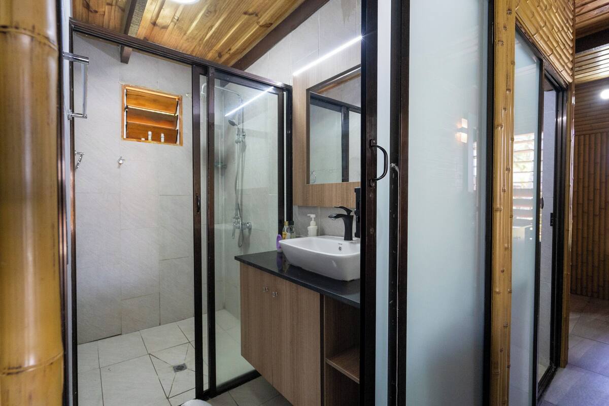 Une salle de bain moderne avec une douche à parois de verre, un lavabo blanc et des meubles en bois.