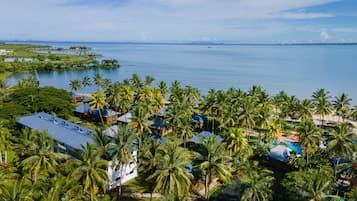 Un resort tropicale con diversi edifici in stile bungalow, una piscina e vista sull'oceano.