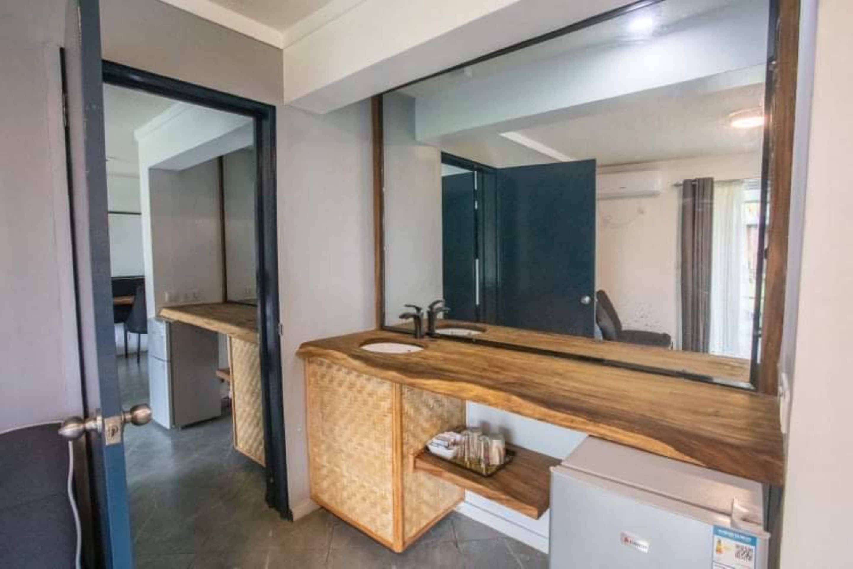 A modern bathroom with a wooden vanity, a large mirror, and a built-in sink.
