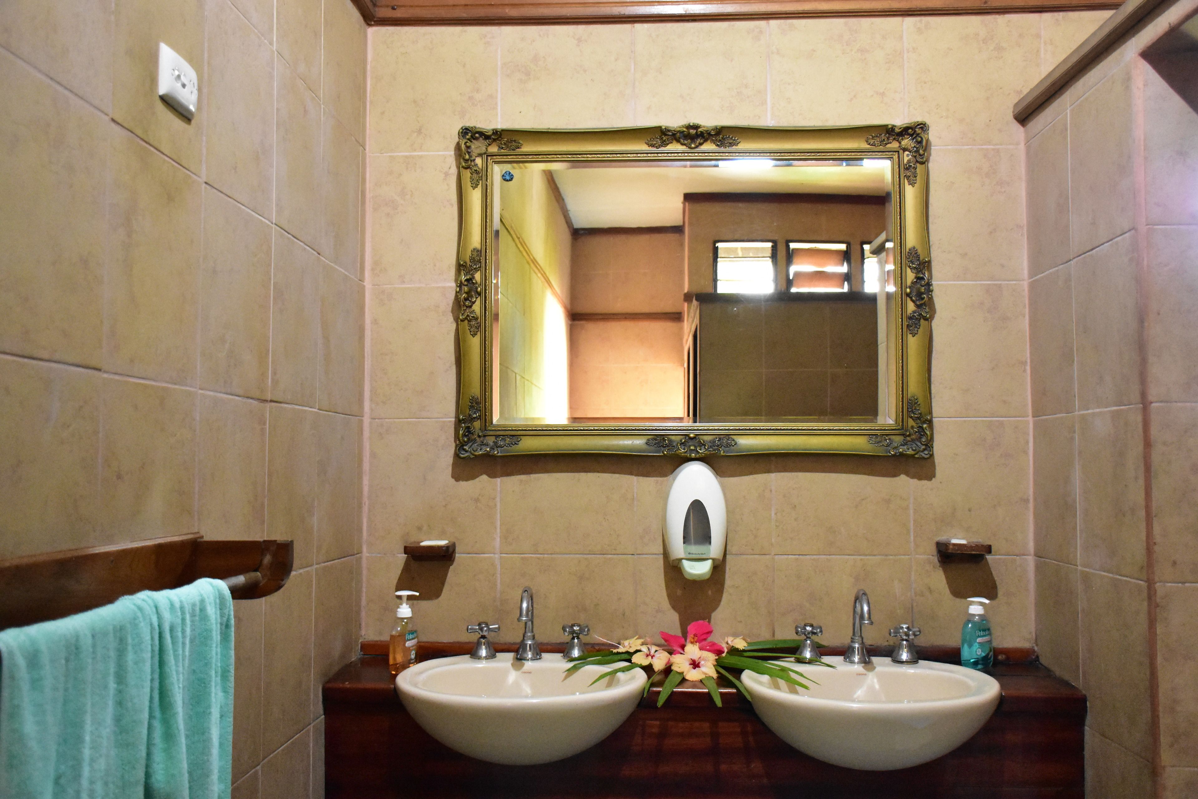 Un baño con dos lavamanos, un espejo y un perchero para toallas.