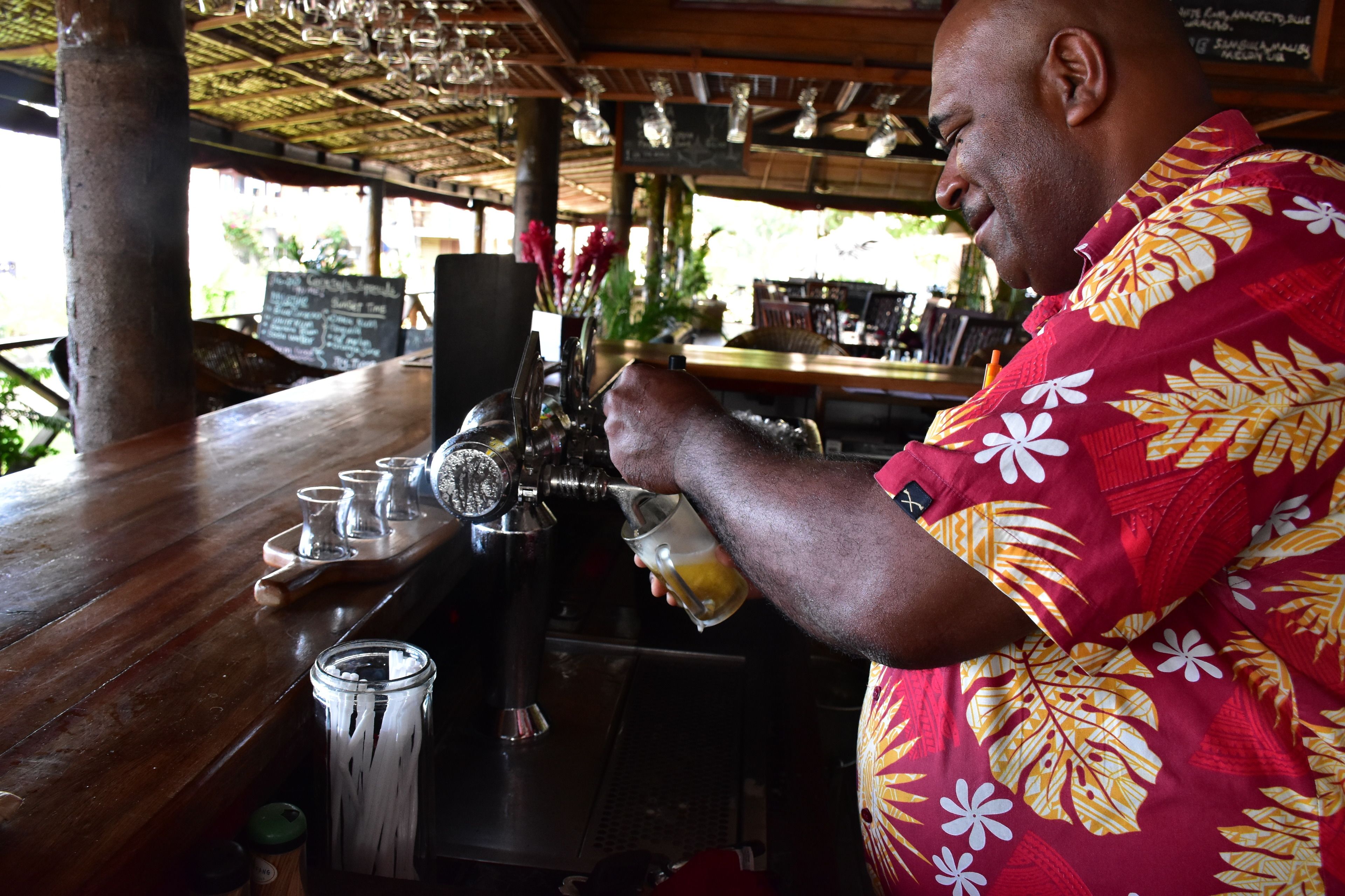 A person pouring a drink from a tap into a glass at a bar.