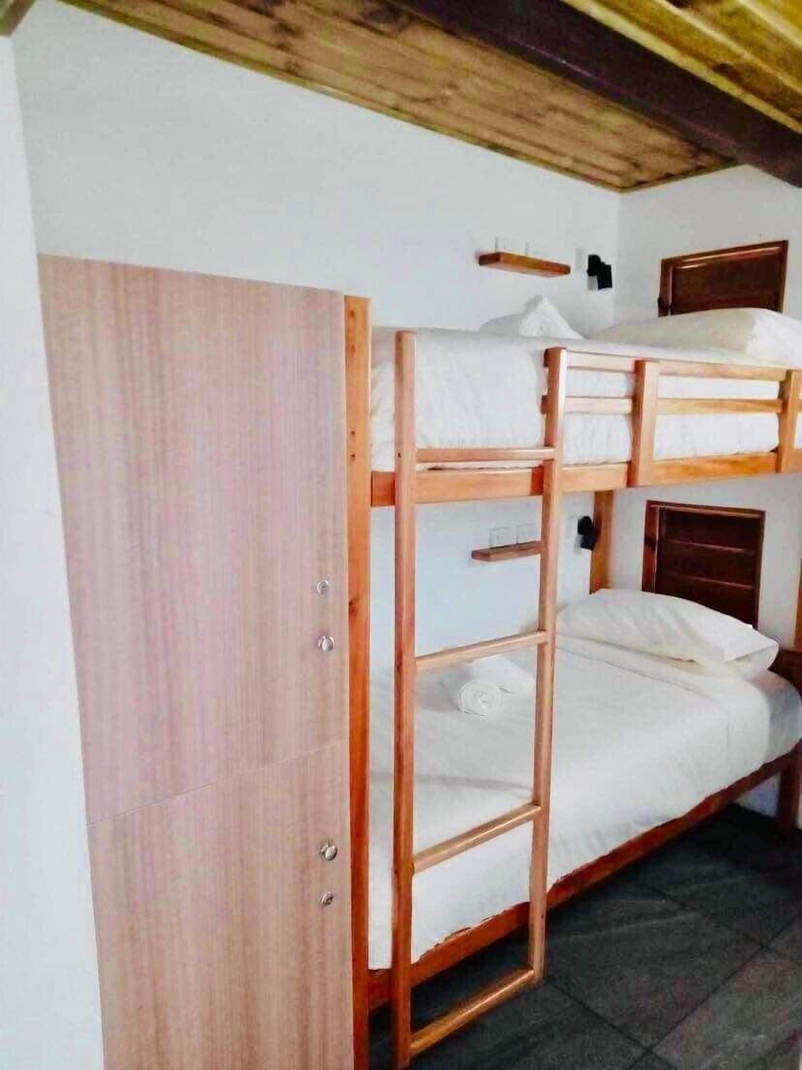 Habitación con literas, un armario de madera y una escalera de madera.