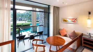A modern hotel room with a balcony, a sofa, a round wooden table, and a painting on the wall.