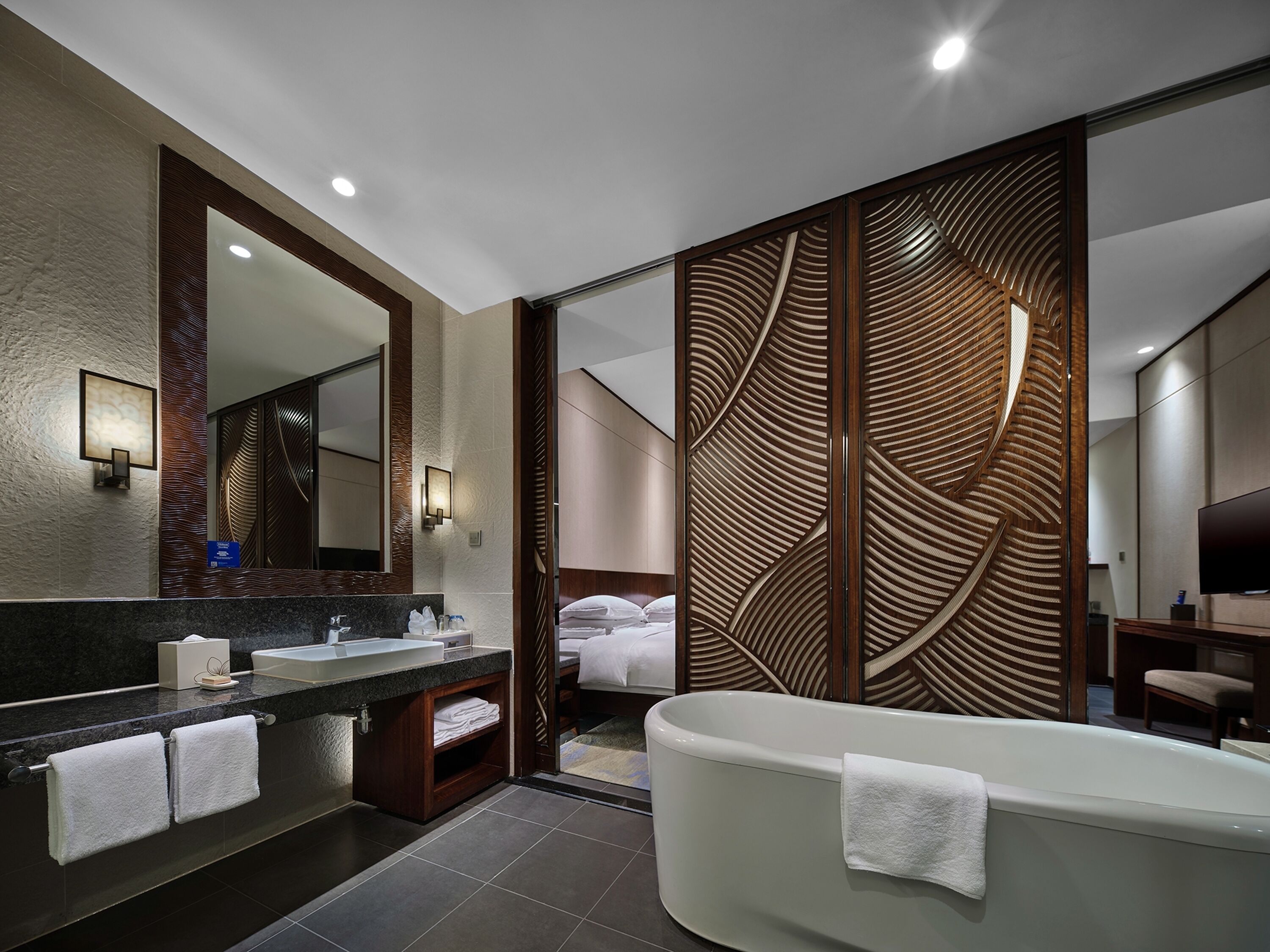 Un bagno moderno con uno specchio grande, una vasca e un mobile lavabo con lavandino e porta asciugamani.