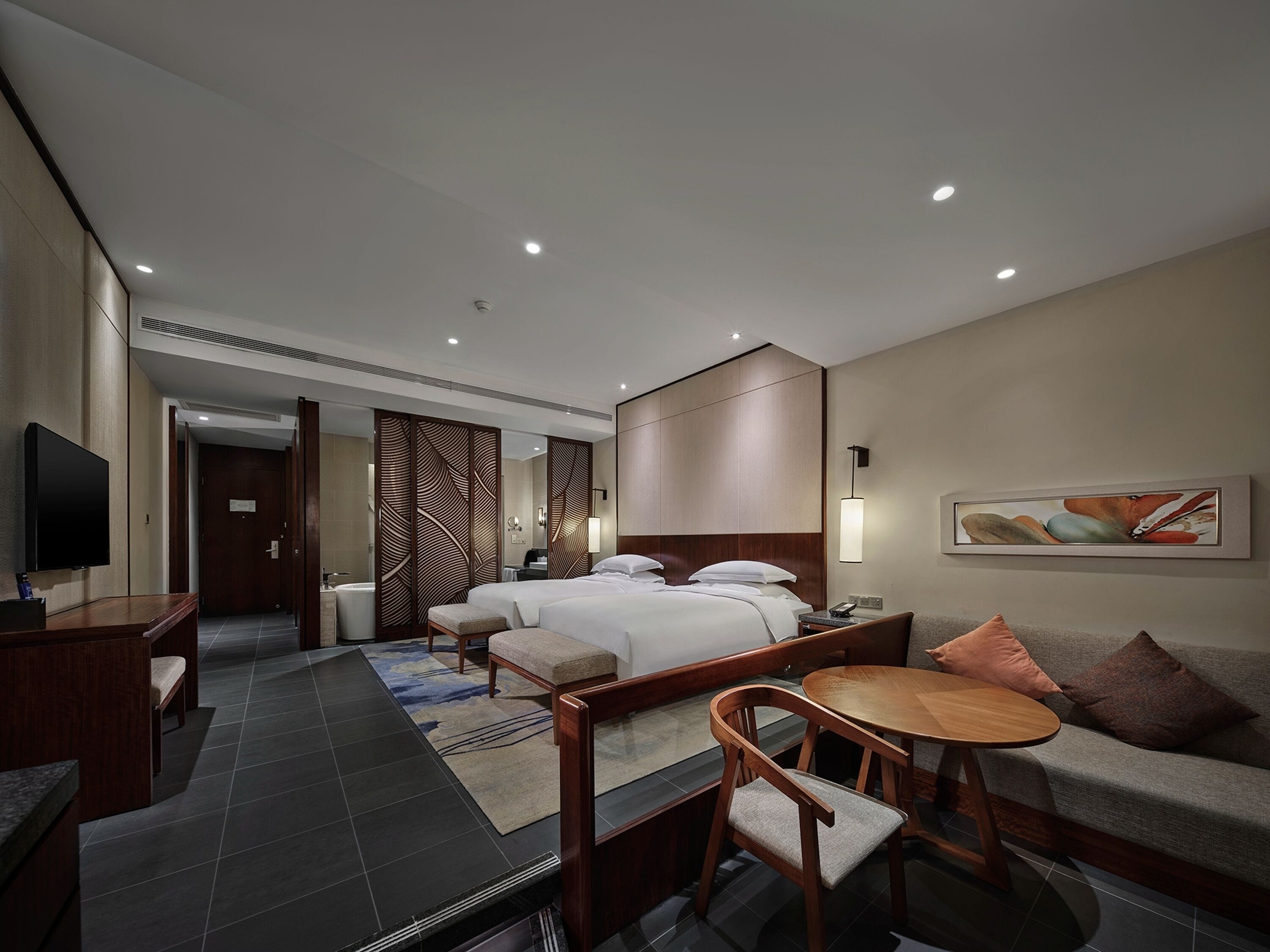 Una habitación de hotel con una cama, un escritorio, una silla, un sofá y un televisor.