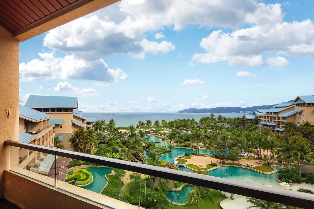 A resort with multiple swimming pools, palm trees, and a view of the ocean.