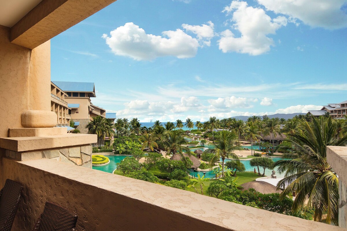 A resort with multiple swimming pools, lush greenery, and a clear blue sky.