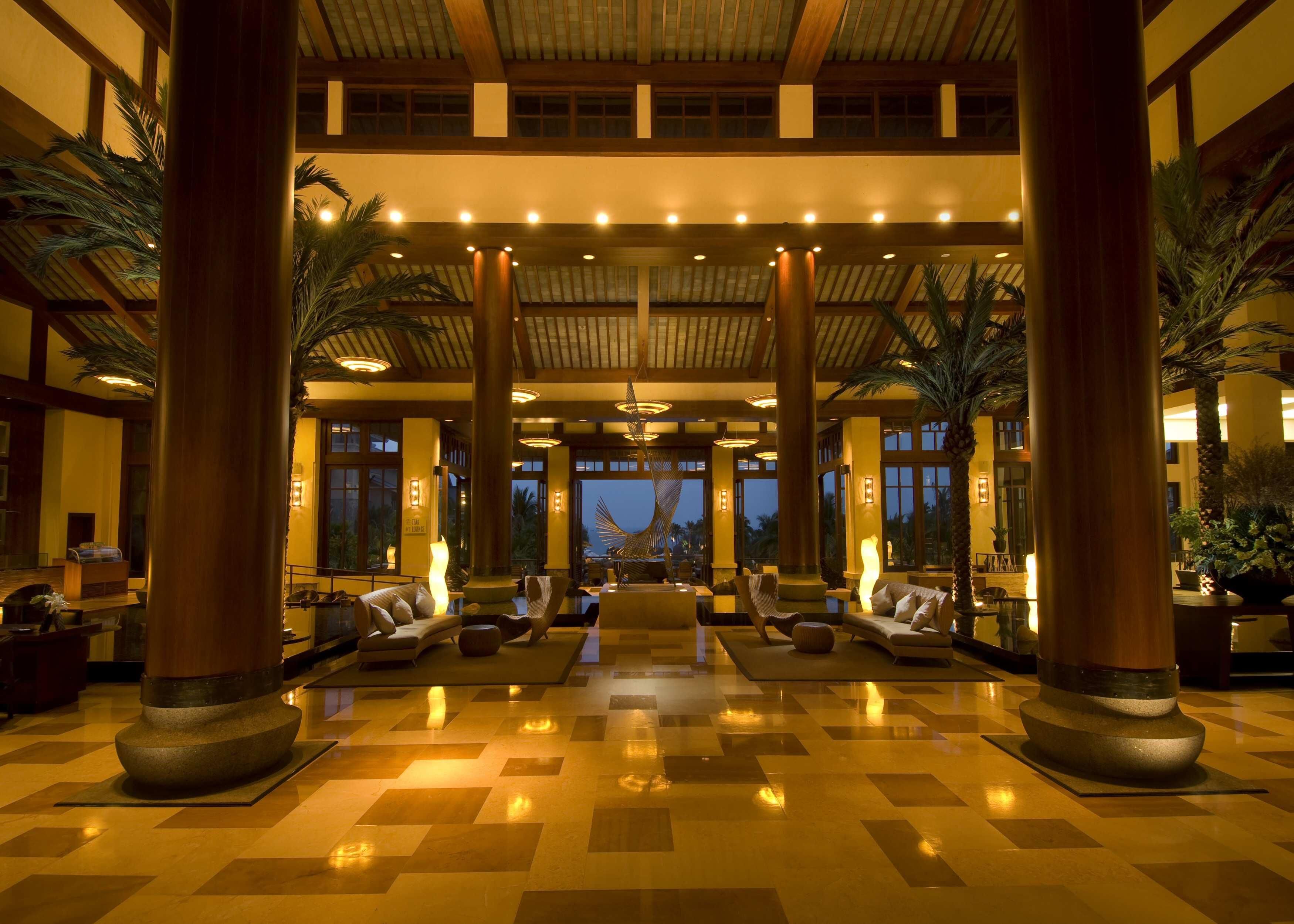 A spacious lobby with a checkered floor, large pillars, and seating areas.