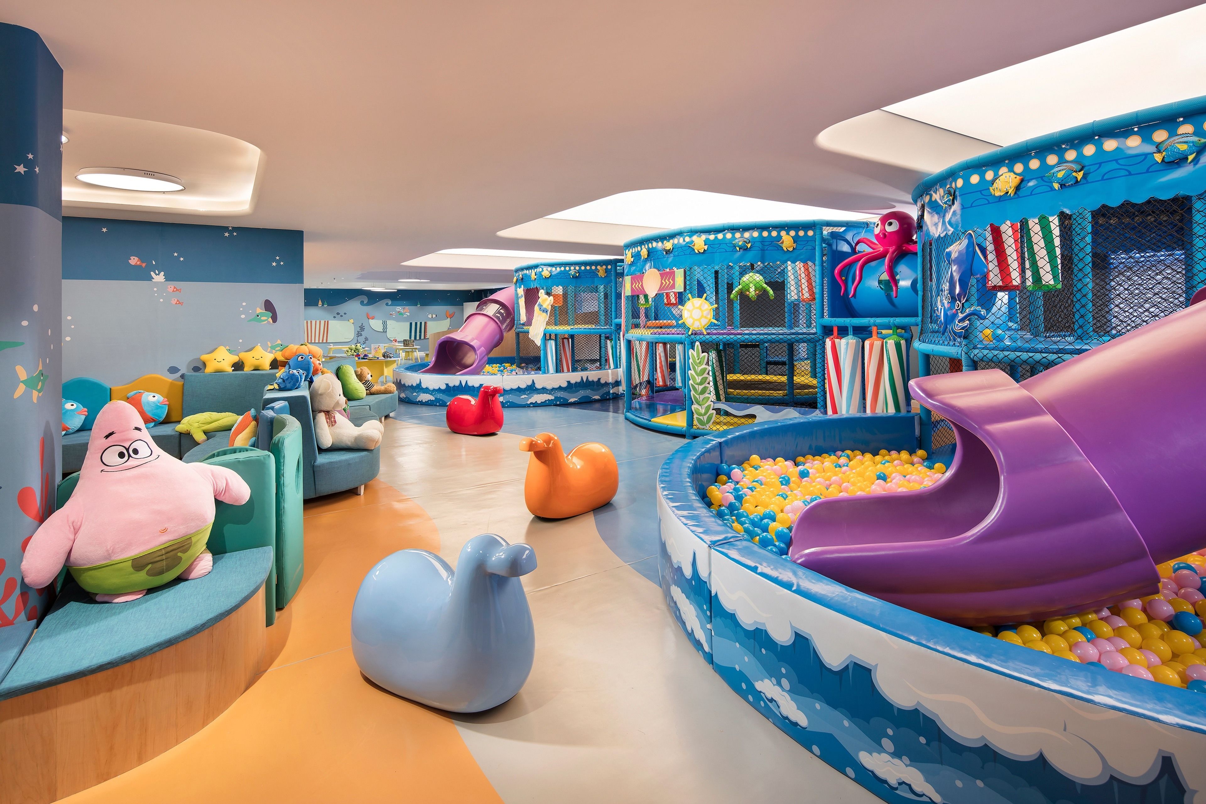 Un espace de jeux pour enfants avec des toboggans, des piscines à balles et des structures de jeux à thème.