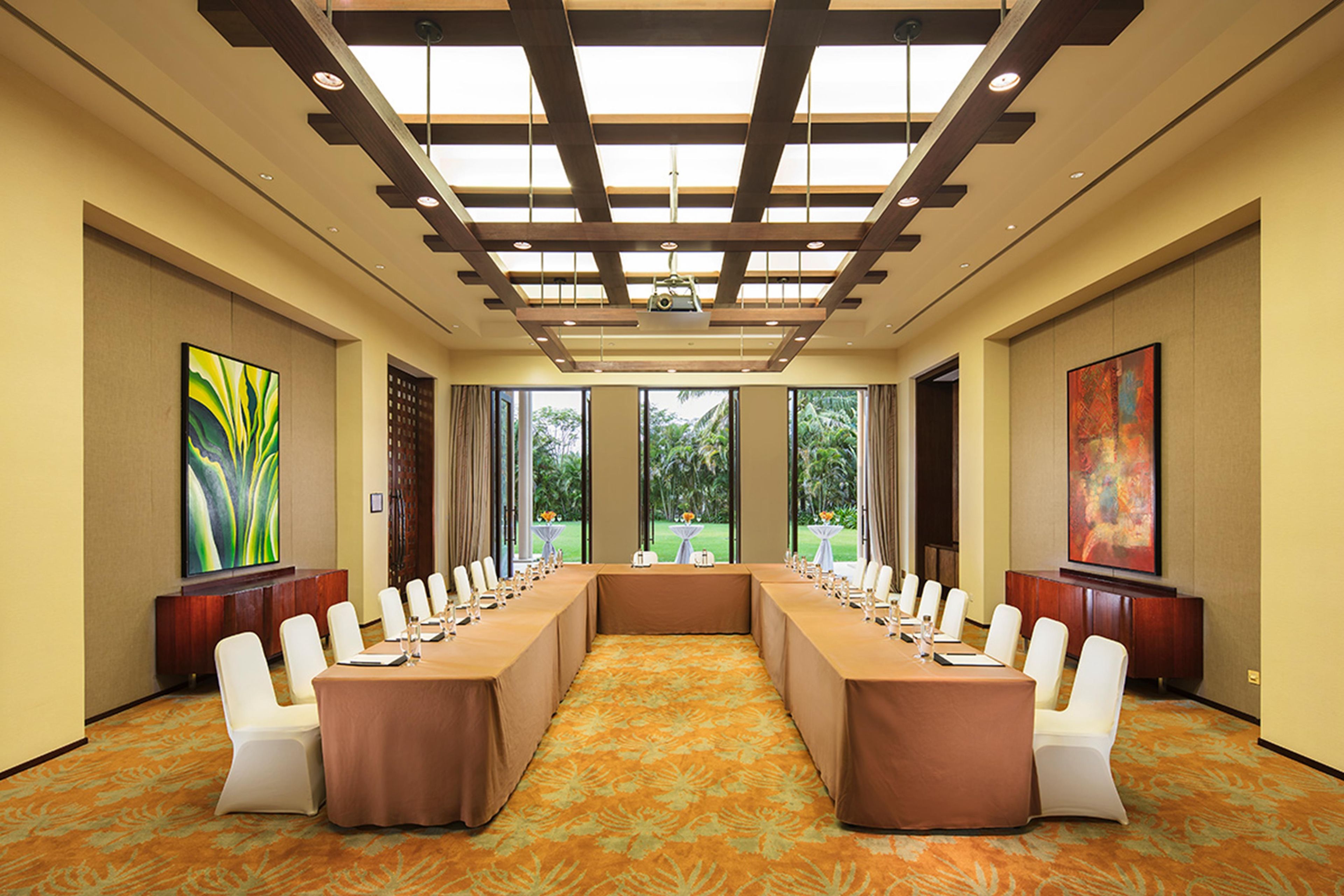 A conference room with a long table, white chairs, and large windows.