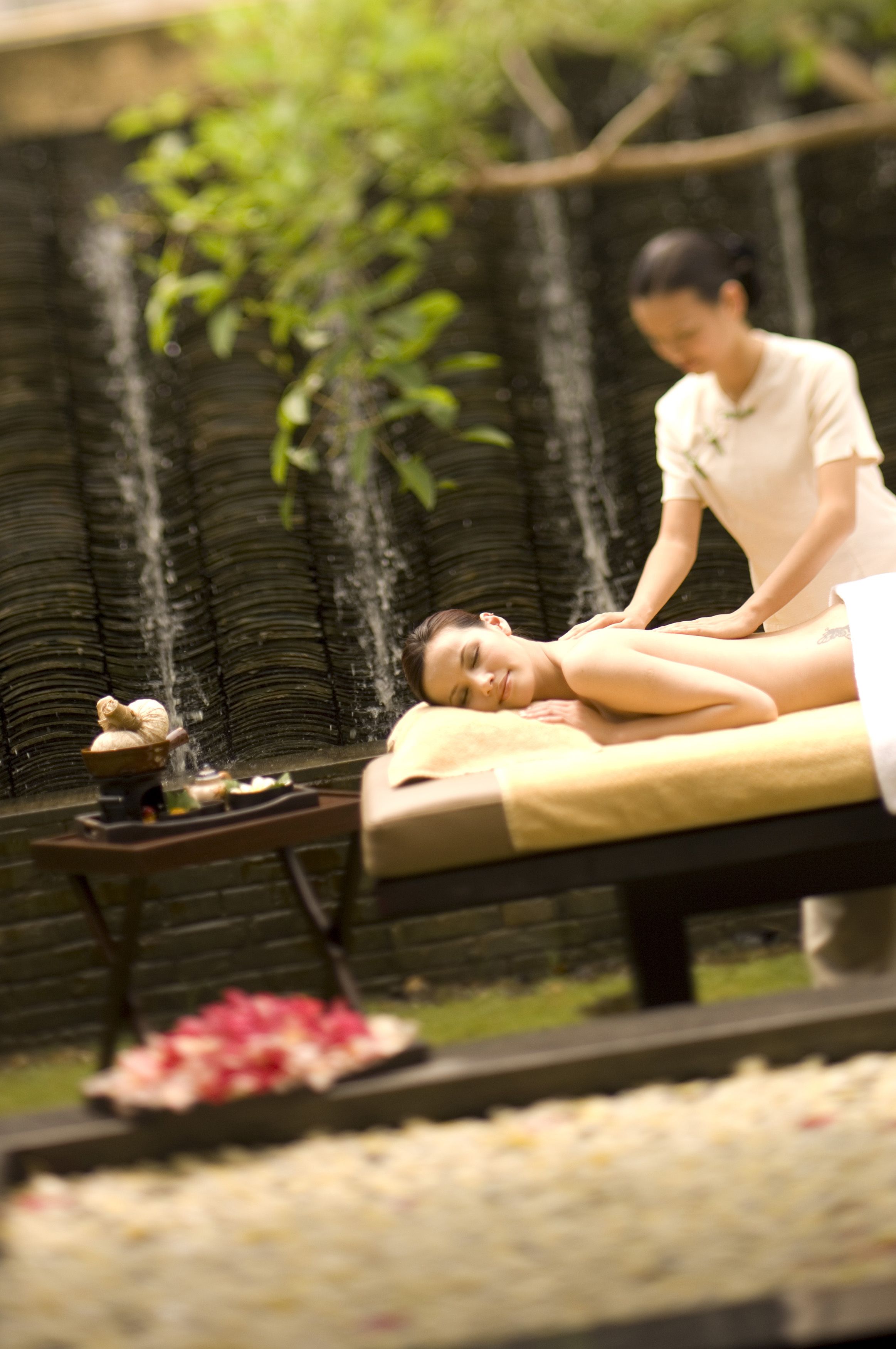 Une personne reçoit un massage dans un spa, avec une cascade en arrière-plan.