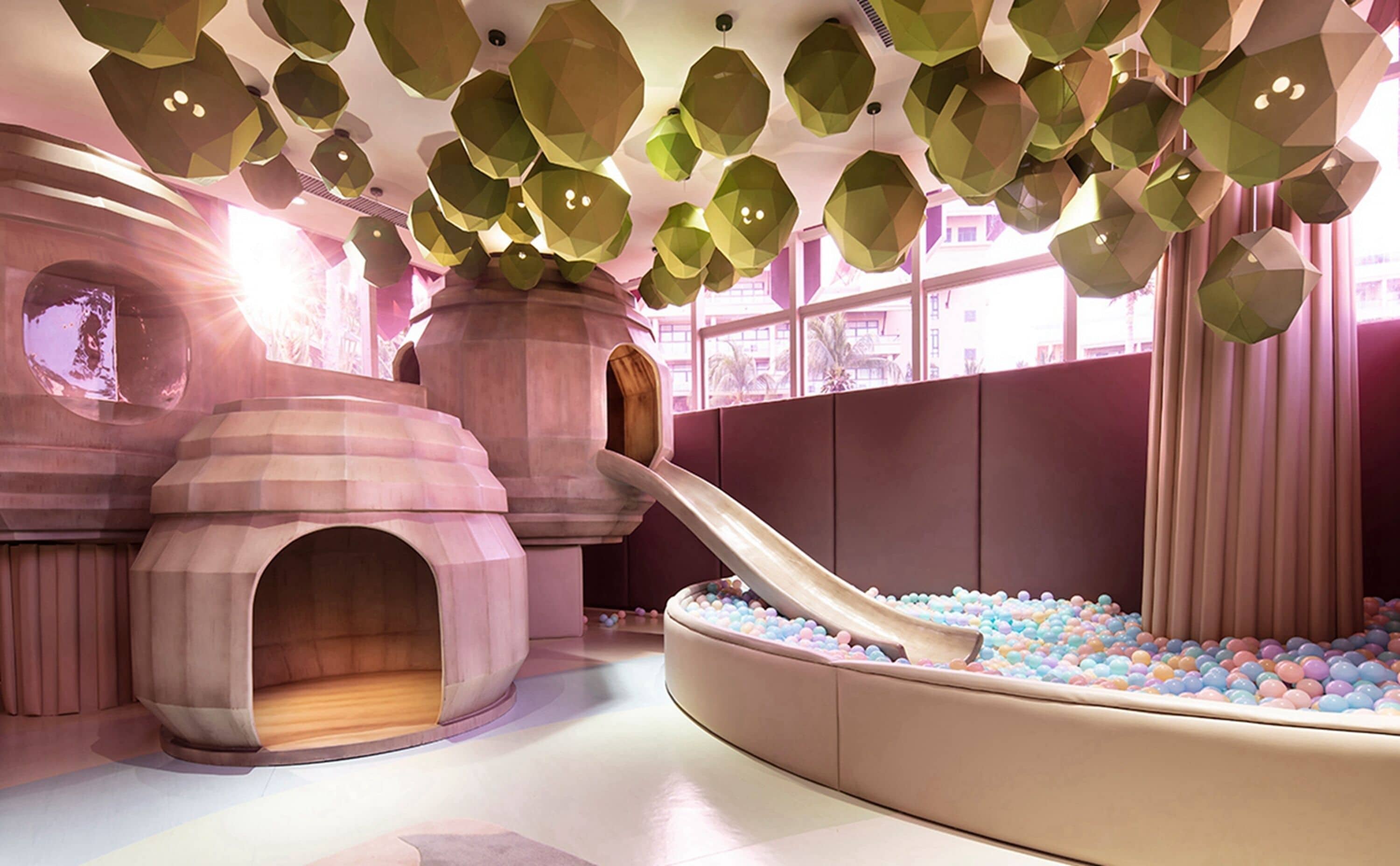 A children's play area with a slide, ball pit, and unique geometric ceiling design.