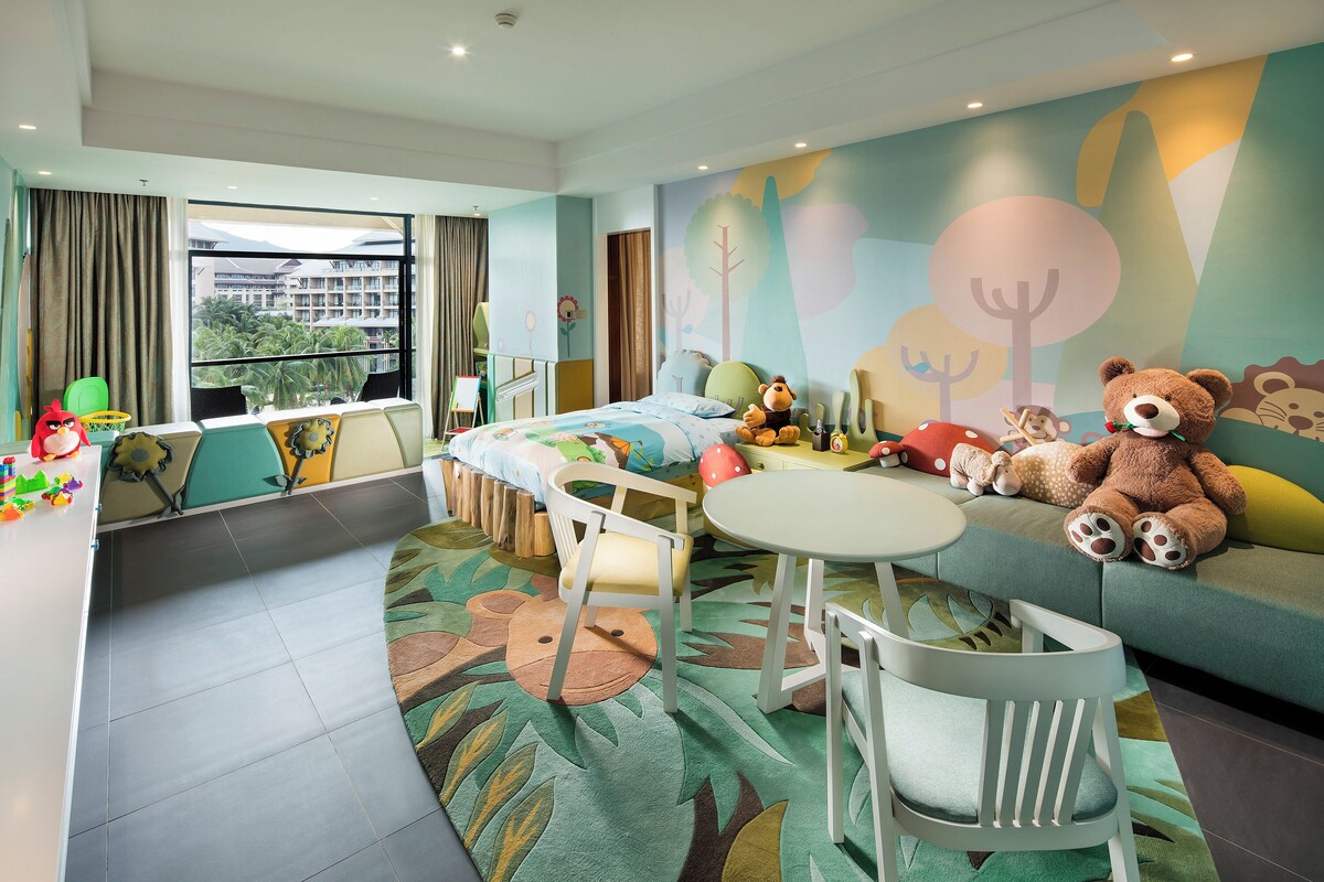 Une chambre d’enfant avec un lit, une petite table, des chaises et un canapé.