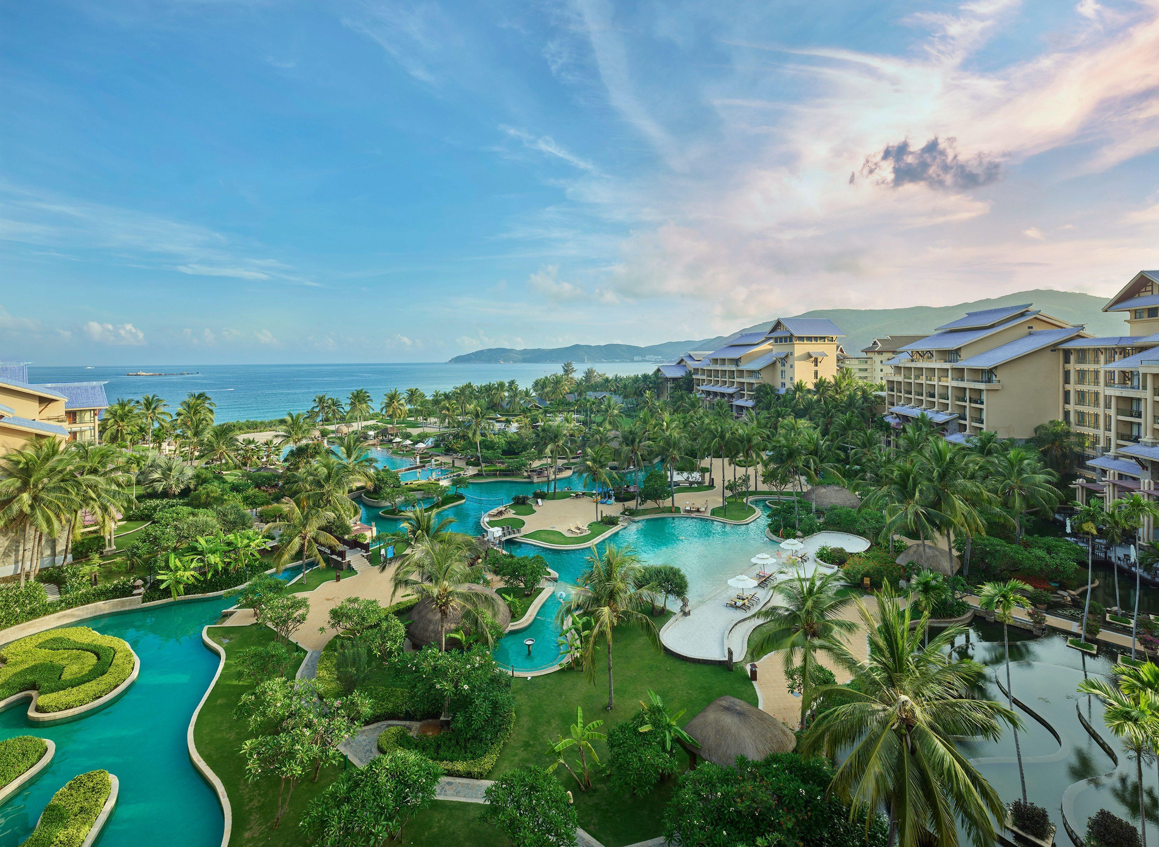 A resort with multiple swimming pools, lush greenery, and beachfront views.