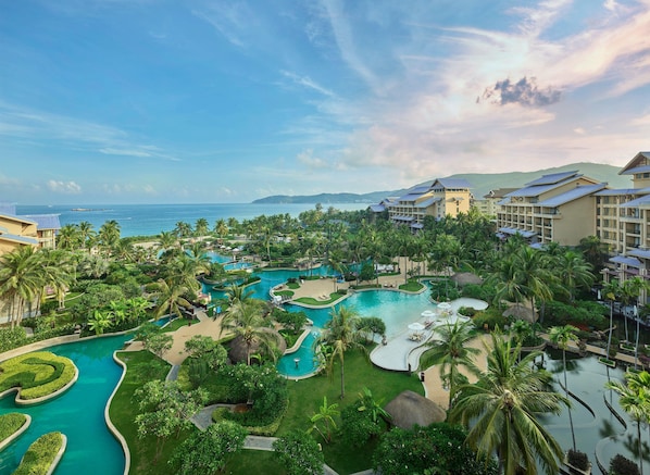 A resort with multiple swimming pools, lush greenery, and beachfront views.
