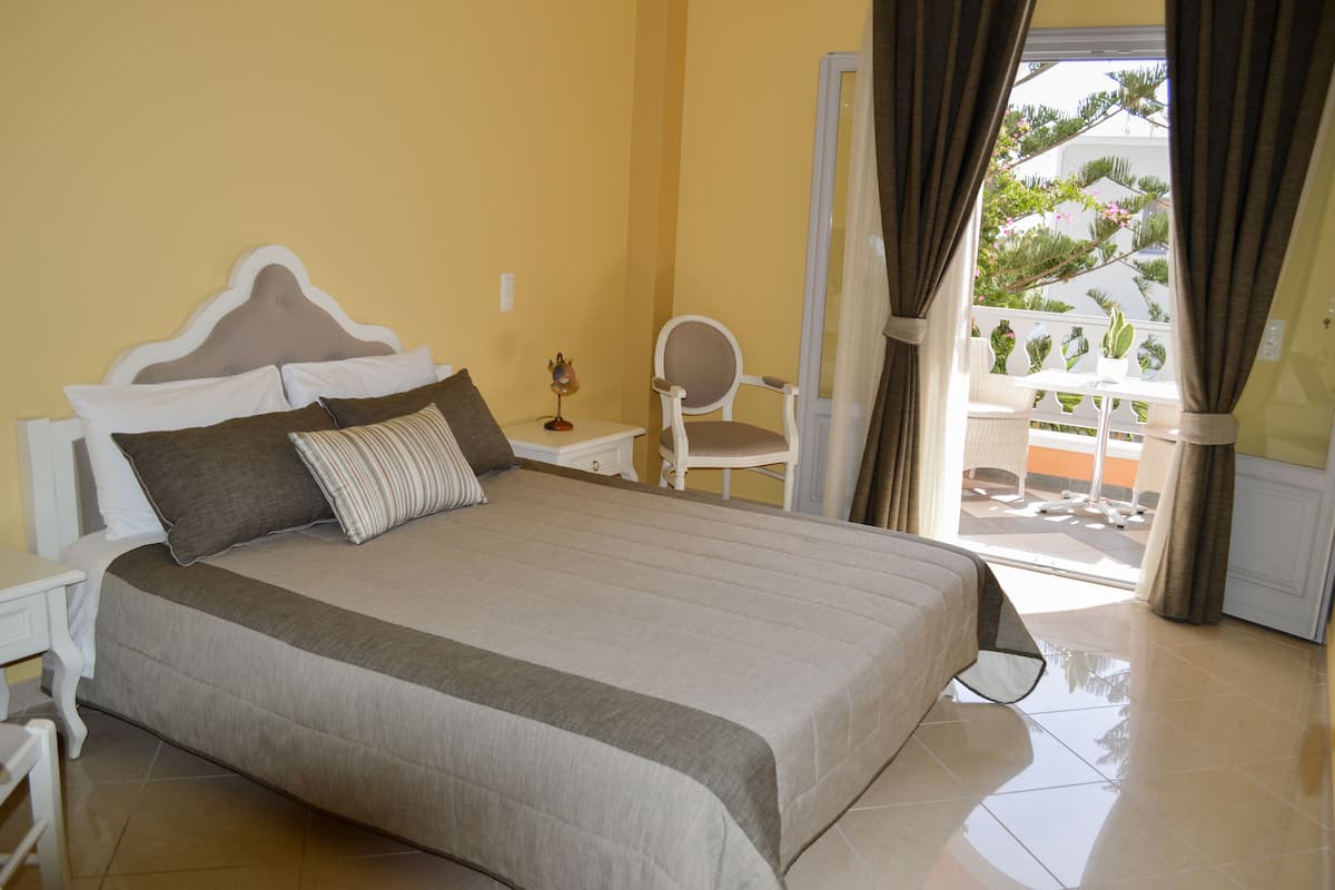 A bedroom with a large bed, a nightstand, a chair, and a view of the outside balcony.