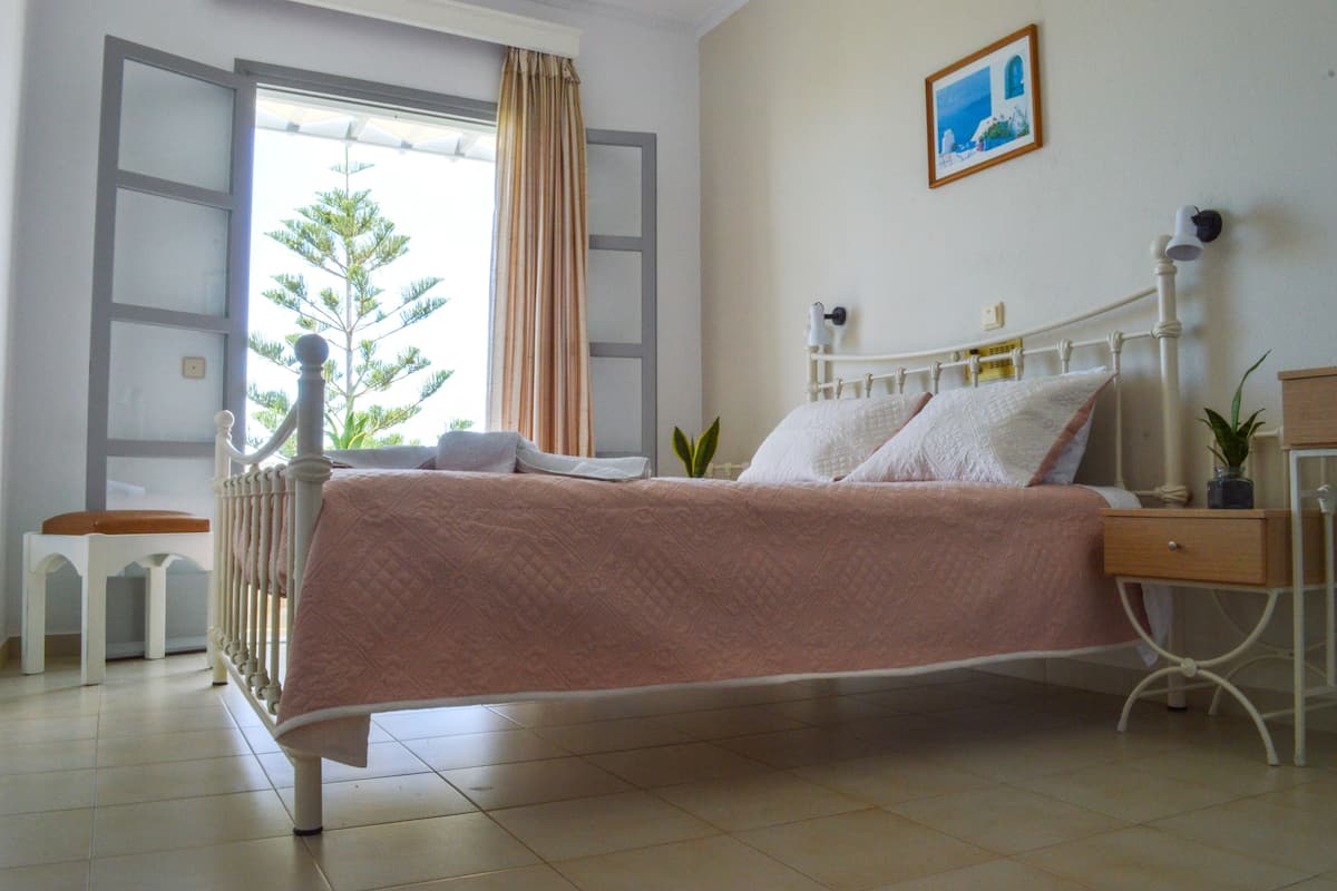 A bedroom with a bed, bedside table, and a window with curtains.