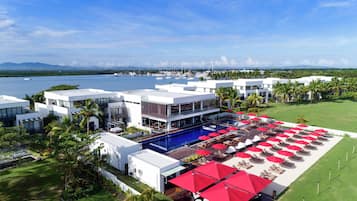 A resort with a pool area, multiple buildings, and a marina in the background.